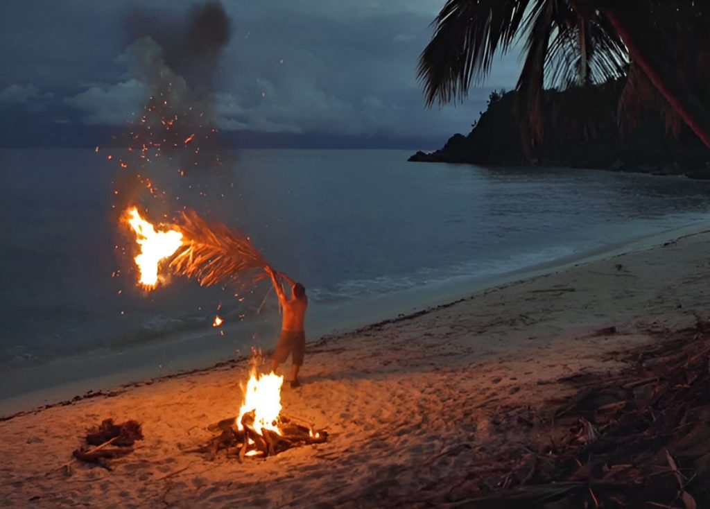 Un homme qui fait un SOS avec un feu sur une plage